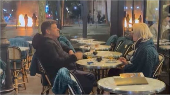 كأن شيئاً لم يحدث.. زوجان يحتسيان مشروبهما وسط نيران باريس